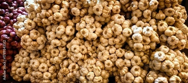 Obraz Fresh garlic bulbs and red onions at a farmers market stall