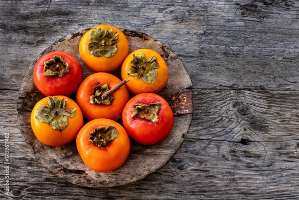 Obraz Ripe persimmon fruits in the wooden bowl. Trabzon or cennet hurması 
