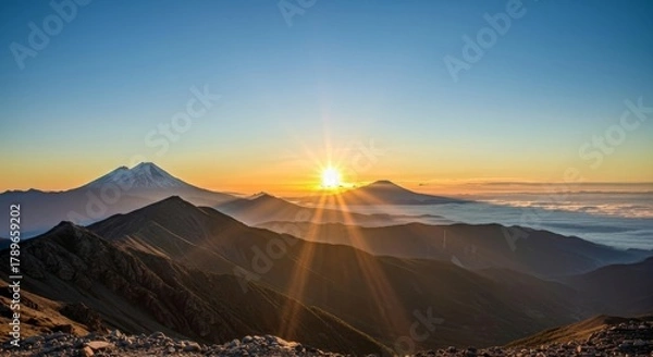 Fototapeta Majestic Sunrise over a Mountain Range with Dramatic Sun Rays and Clouds