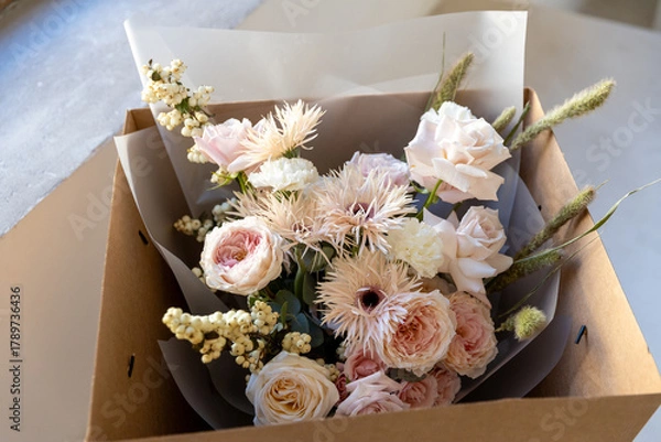 Fototapeta Mixed flower bouquet with roses, gerberas, and berries, carefully placed inside a cardboard delivery box, ready for gift giving