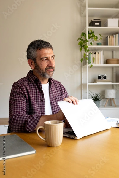 Obraz Thoughtful man closing laptop, ending remote work day