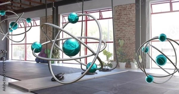 Fototapeta Hanging large orbital sculpture catching window light in warehouse studio, showing suspension ropes