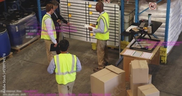 Obraz Gathering warehouse team wearing safety vests checking schedule at staging, whiteboard and boxes