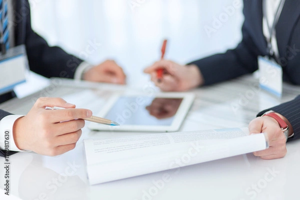 Obraz 資料を見せて打ち合わせをするビジネスマンとビジネスウーマン 