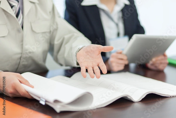 Obraz 打ち合わせをする作業着姿の男性とビジネスウーマン 