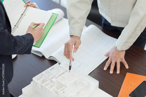 Obraz 打ち合わせをする作業着姿の男性とビジネスウーマン 