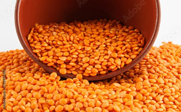 Fototapeta Red lentil background. Beautiful red lentils spill out of a clay cup.