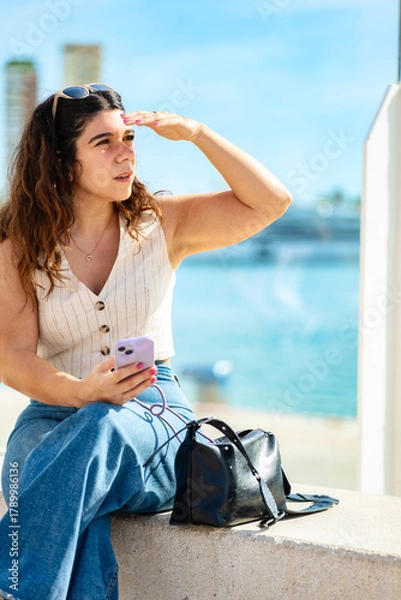 Obraz Woman with cell phone shielding herself from the sun