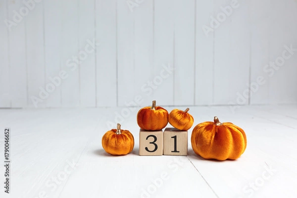 Fototapeta On an empty wooden background lies a cube with the number three and a pile of pumpkins nearby