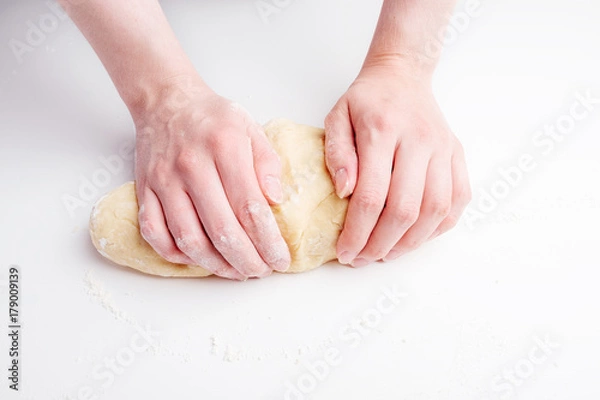 Fototapeta Making dough by female hands on white table
