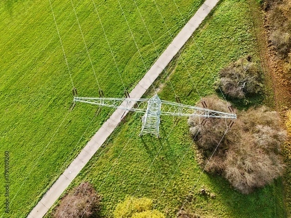 Fototapeta Aerial View of High Voltage Power Line Tower in Green Landscape