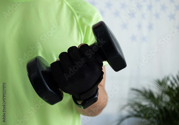 Obraz Close up of an unrecognizable man wearing a sports glove while lifting a dumbbell. Concept of strength, training, fitness detail, and active lifestyle