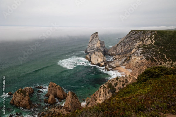 Obraz Dramatic coastal cliffs and rock formations at Cabo da Roca, Portugal, with mist rolling over the Atlantic Ocean on a moody day