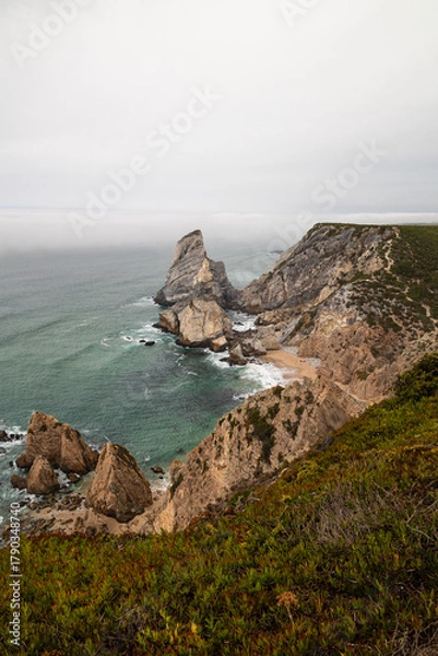 Obraz Vertical view of Cabo da Roca's rugged cliffs and turquoise waters beneath low-hanging mist on Portugal's Atlantic coast