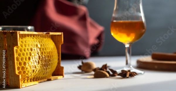 Fototapeta High-quality photo with shallow depth of field focusing on natural honeycomb. Blurred background shows whiskey and spices. Organic food texture, natural sweetener, or premium beekeeping product