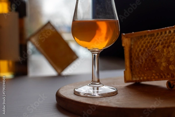 Fototapeta Elegant glass of amber whiskey served with natural honeycomb on rustic wooden stand. Concept of whiskey tasting, honey-flavored spirits. Premium alcoholic beverage with organic honey cells