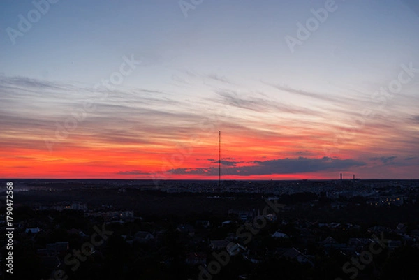 Fototapeta Wide cityscape view with dramatic sunset clouds and skyline