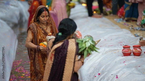 Obraz Women devotees stand in the river during Chhath Puja in Bihar, offering fruits and soup to the rising Sun God.