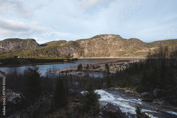 Fototapeta Powerful Reiarsfossen waterfall near Setesdal Valley, Norway. Water cascades over dark cliffs surrounded by pine forest, symbol of wild Nordic nature