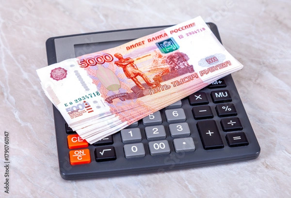 Fototapeta Stack of five thousandths banknotes of russian roubles with calculator