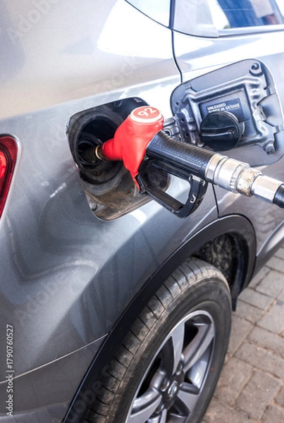 Obraz Refueling the car at a gas station fuel pump. Refueling valve is inserted into the fuel filler neck. Fuel nozzle to release fuel into passenger car