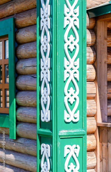 Fototapeta Traditional wooden handmade carved decorations on the corner of a wooden log house. Wooden house with carved wooden trim