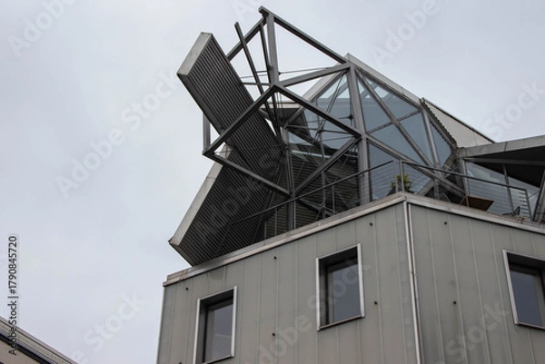 Obraz Modern architectural structure featuring a unique angular design with glass and metal elements, showcasing innovative construction techniques and contemporary aesthetics in urban environment