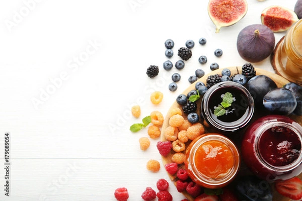 Obraz Szklane słoiki z różnego rodzaju dżemami i jagodami na drewnianym stole