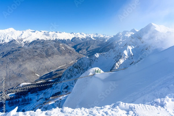 Fototapeta A view of snowy peaks with a sunbeam on the horizon.