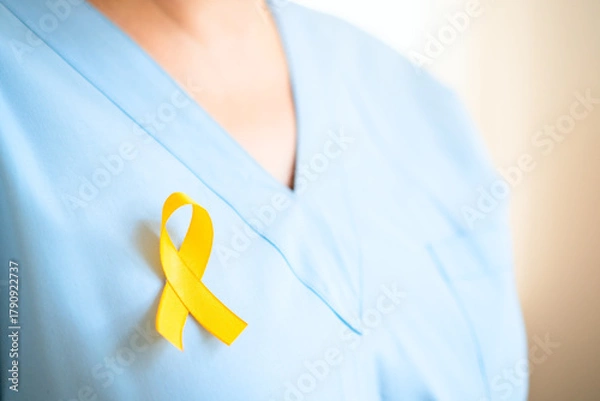 Obraz Close up of healthcare professional woman in uniform with yellow ribbon. Represents support for children with cancer, medical care, timely diagnosis, family assistance, and health awareness.