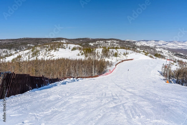 Fototapeta Ski trail limited by a wooden fence against the backdrop of a picturesque landscape of the Ural Mountains.