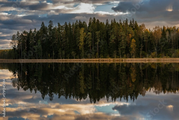 Obraz Colourful autumn landscape in the forest next to a lake during sunset, water reflections and colourful sky