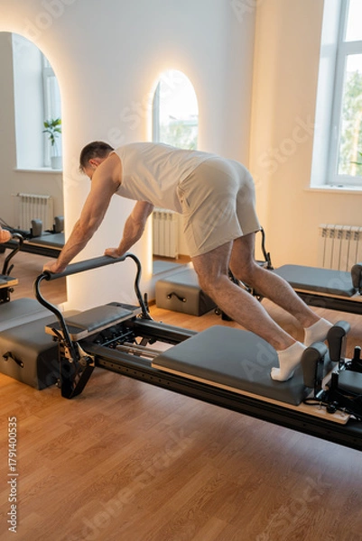 Fototapeta Dynamic reformer plank, individual executes dynamic plank with tension on reformer for endurance