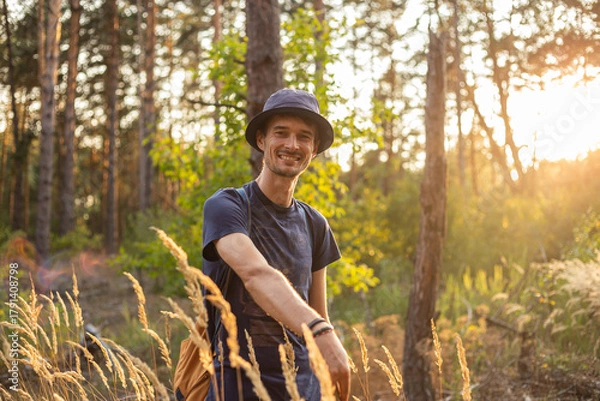 Obraz Handsome young caucasian man in the forest woods with shining spikelets in black panama