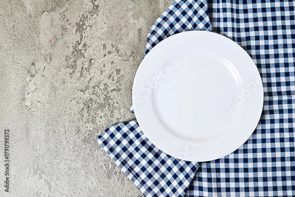 Fototapeta Top view of empty white plate with napkin. Grey or gray cement on the background. copy space, empty, free, negative, text, design. flat lay. high angle, above.