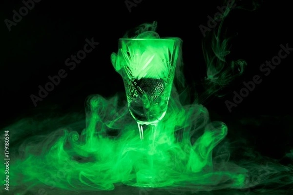 Obraz Smoke into cocktail glass on a black background. Witch potion background for Halloween. Unusual bar drink.