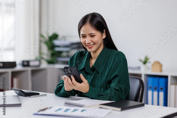 Fototapeta Business asian woman having phone conversation with client in office. young woman using smart phone. Woman Hands Using Mobile Phone in the Office

