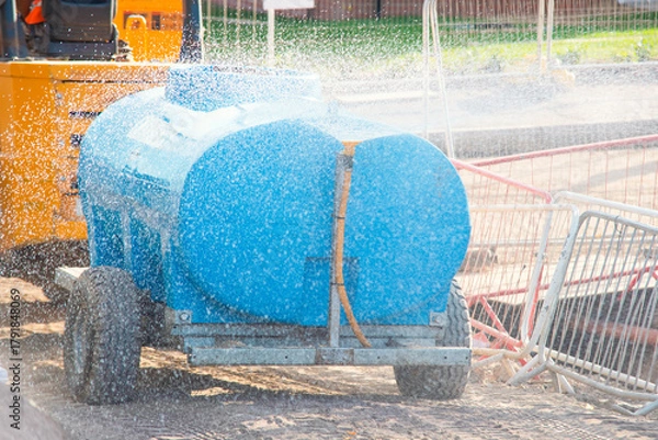 Fototapeta Construction site water spraying device used for dust control during hot summer days work