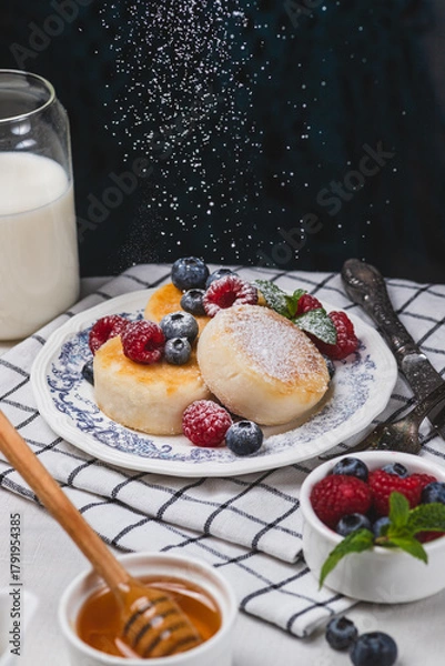 Fototapeta Cheesecakes with powdered sugar and berries on a plate