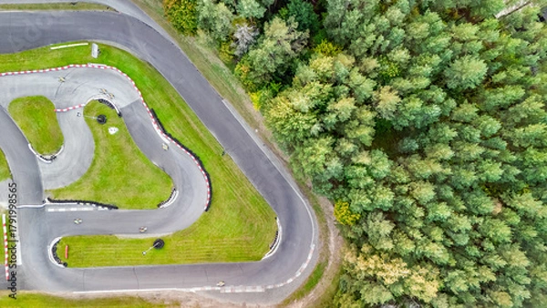 Fototapeta Aerial drone view of karting race track in green forest with racing go-karts cars driving, kart racing open wheel motorsport
