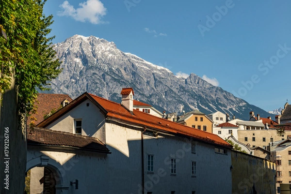 Fototapeta Alpine Town with Red Roofs and Snowy Mountain Peaks under Clear Blue Sky