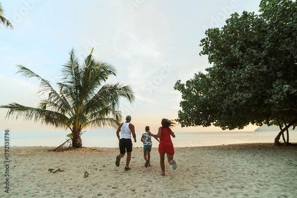 Fototapeta A happy time in the life of a family is an evening fun walk along the beach in Thailand.