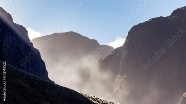Fototapeta Mountain landscape, misty and sunlit, with rocky peaks under a clear blue sky, scenic view, copy space