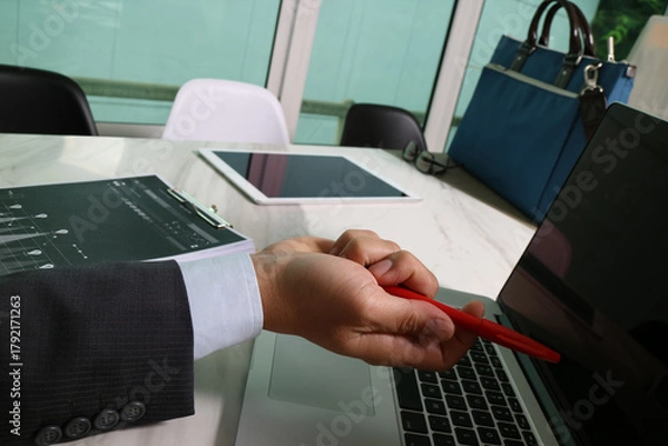 Obraz Businessman analyzing data with laptop and document in office