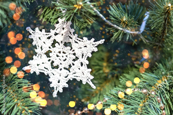 Fototapeta Handmade knitted snowflake decoration on Christmas tree. Copy space