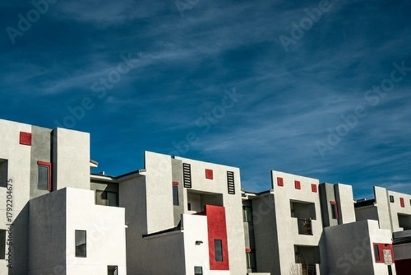 Fototapeta Modern white and red apartment buildings under a deep blue sky showcasing contemporary urban residential architecture