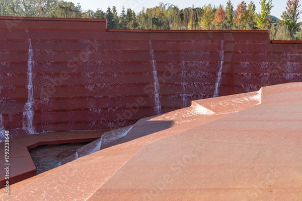 Fototapeta Architectural water feature with cascading terraces, where water flows down rust-colored steps, creating a dynamic scene. Water amphitheater or canyon in Krasnodar's city park, or Galitsky Park