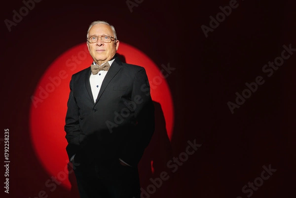 Fototapeta  successful, experienced senior businessman isolated on red spot light background with copyspace. Personal Growth Keynote Speaker.
