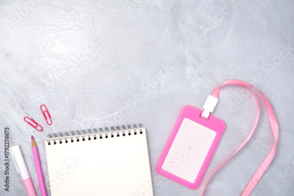 Fototapeta Pink plastic badge with book and stationery on white stone texture background. Template designed for employees of company