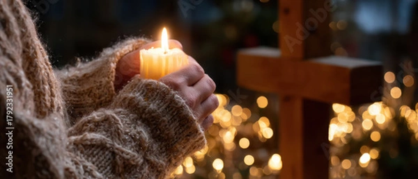 Fototapeta Realistic close-up of hands lighting a candle before a wooden cross on Christmas Eve, warm firelight, shallow depth of field, intimate devotional mood